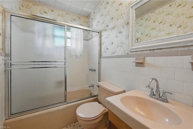 8084 Lynnbrook Dr, Norfolk, VA 23518 - bathroom featuring wallpapered walls, a sink, bath / shower combo with glass door, toilet, and tile walls