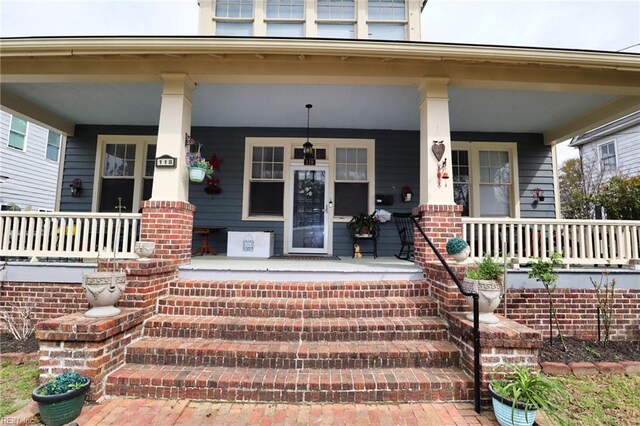 doorway to property with covered porch and brick siding