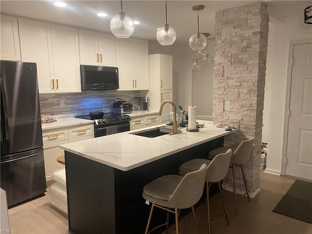 kitchen featuring a sink, black microwave, freestanding refrigerator, backsplash, and electric range
