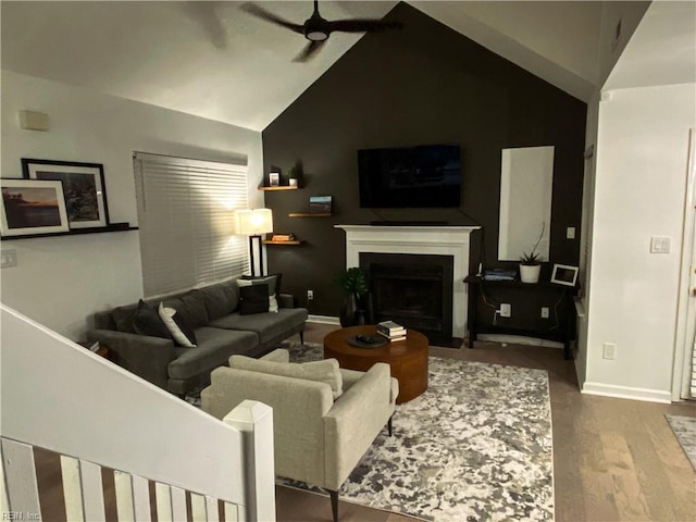 living room with a fireplace with flush hearth, baseboards, ceiling fan, and wood finished floors