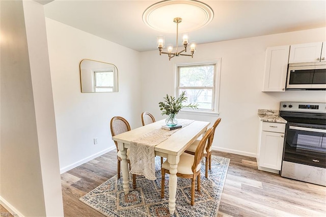 dining area with baseboards, a notable chandelier, and light wood-style floors