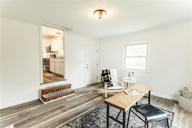 home office featuring ornamental molding, a textured ceiling, baseboards, and light wood-type flooring