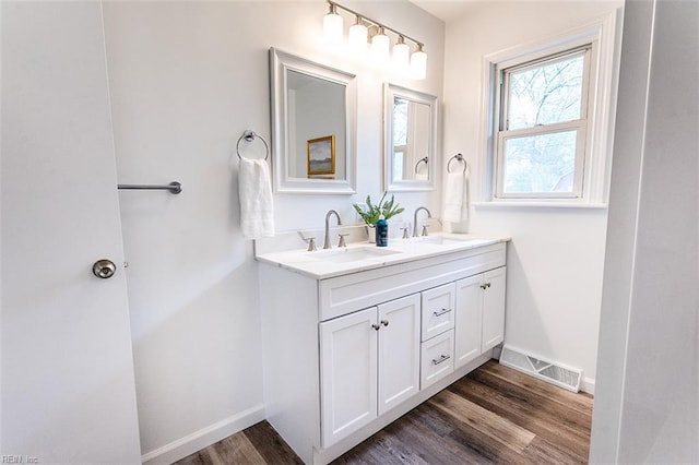 bathroom featuring baseboards, visible vents, wood finished floors, and a sink