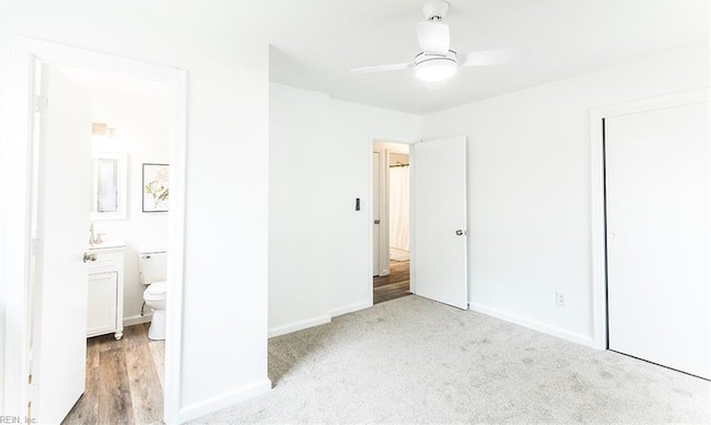 unfurnished bedroom with a closet, carpet, baseboards, connected bathroom, and a ceiling fan