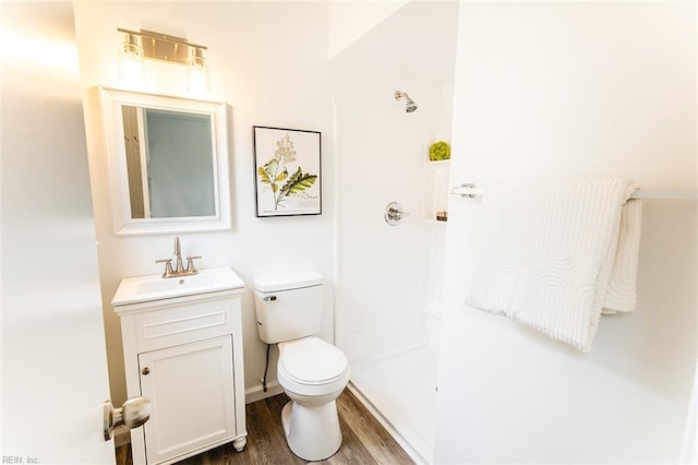 full bathroom featuring wood finished floors, toilet, a shower, and vanity