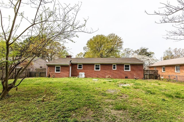 rear view of property featuring a lawn, a chimney, a fenced backyard, and brick siding