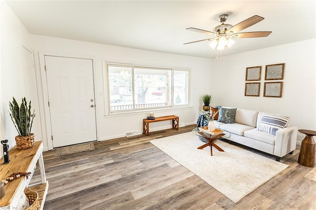 living area with baseboards, wood finished floors, and a ceiling fan