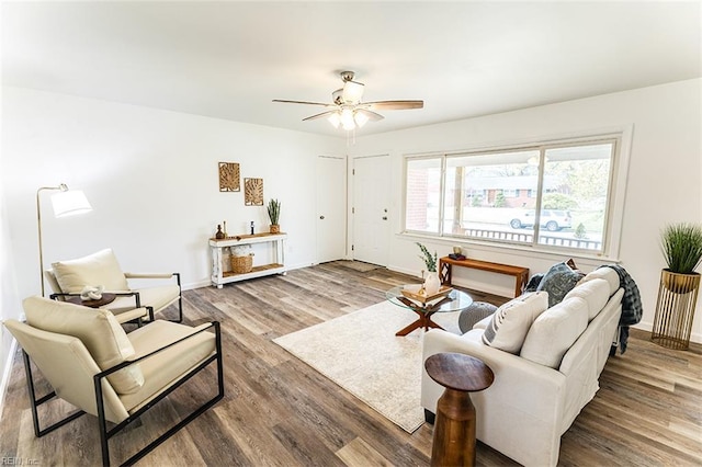 living area with baseboards, wood finished floors, and a ceiling fan