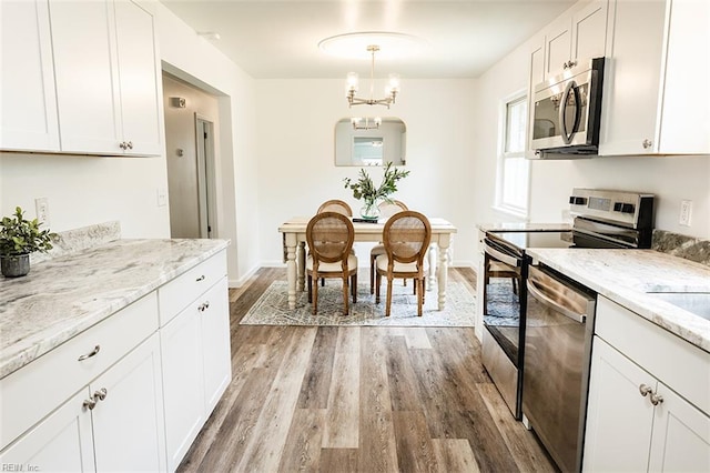 kitchen featuring white cabinets, light wood-style floors, light stone countertops, and appliances with stainless steel finishes