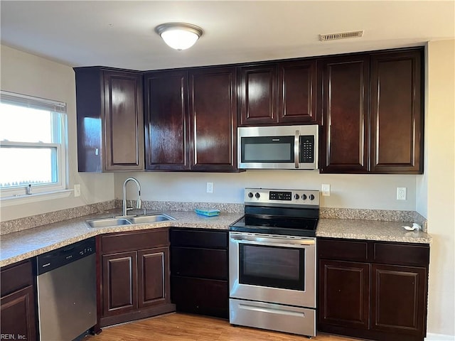 kitchen with light countertops, stainless steel appliances, a sink, visible vents, and dark brown cabinets