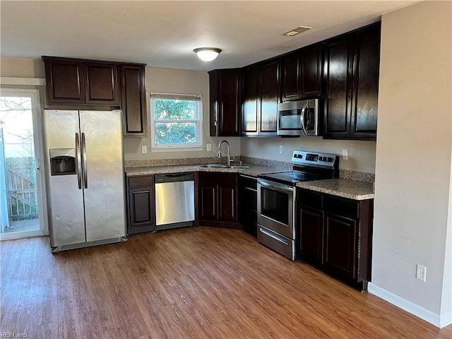 kitchen with a sink, appliances with stainless steel finishes, baseboards, visible vents, and light wood-style floors
