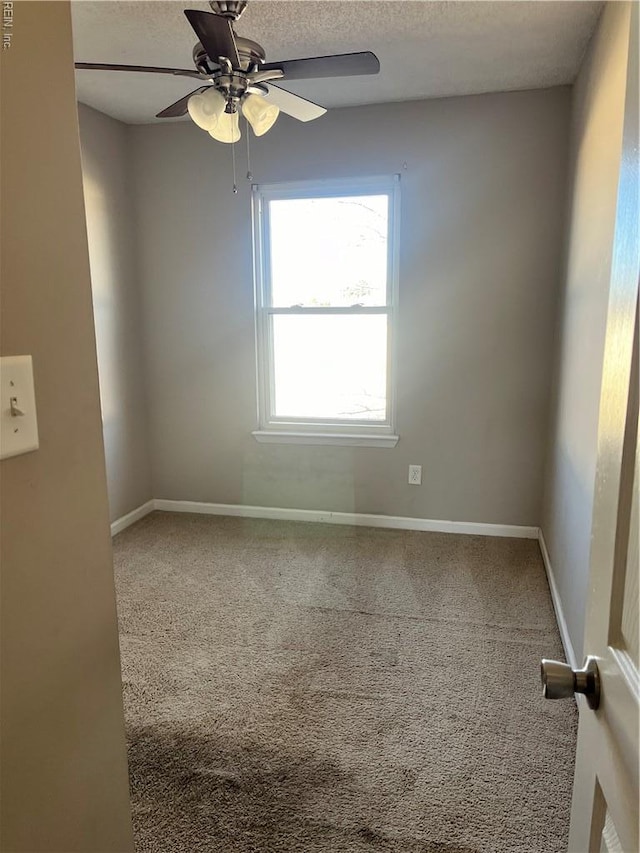 carpeted empty room featuring baseboards, a textured ceiling, and a ceiling fan