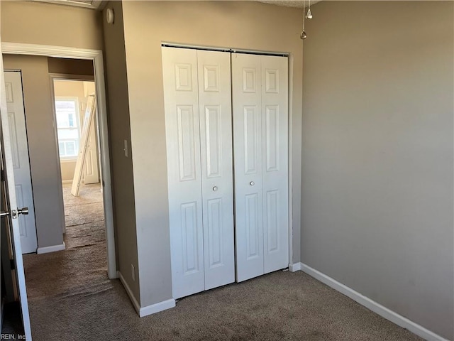 unfurnished bedroom with a closet, carpet flooring, and baseboards