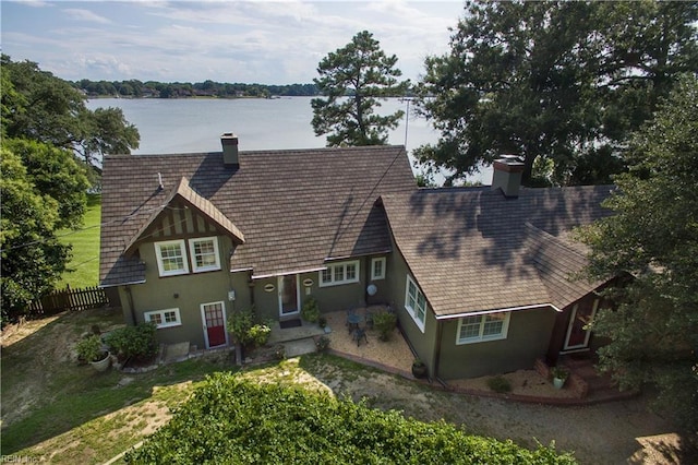 view of front of property featuring a chimney, stucco siding, fence, and a water view