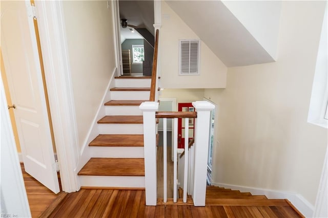 stairway featuring baseboards, a ceiling fan, visible vents, lofted ceiling, and wood finished floors