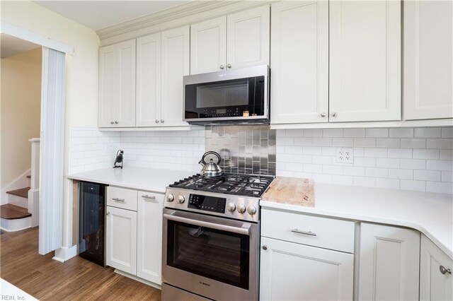 kitchen with light countertops, stainless steel appliances, wine cooler, light wood finished floors, and backsplash
