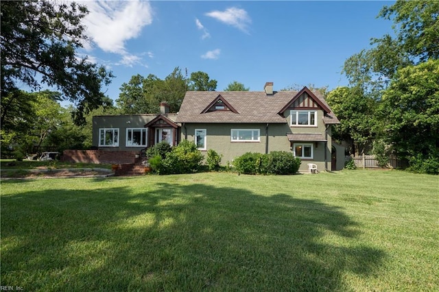 back of house featuring a chimney, stucco siding, fence, and a yard