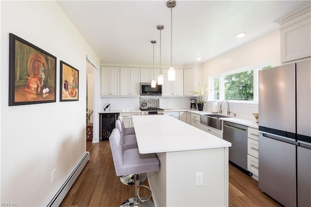 kitchen featuring appliances with stainless steel finishes, a kitchen breakfast bar, backsplash, wine cooler, and a sink
