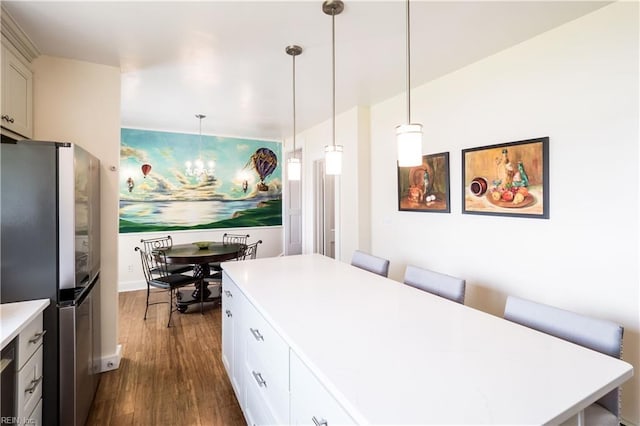 kitchen featuring freestanding refrigerator, an inviting chandelier, light countertops, decorative light fixtures, and dark wood-style floors