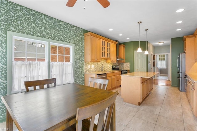 kitchen featuring wallpapered walls, glass insert cabinets, a center island, ceiling fan, and stainless steel appliances