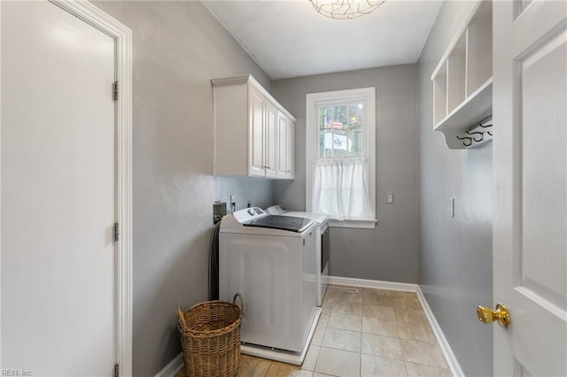 clothes washing area featuring washer and dryer, light tile patterned floors, baseboards, and cabinet space