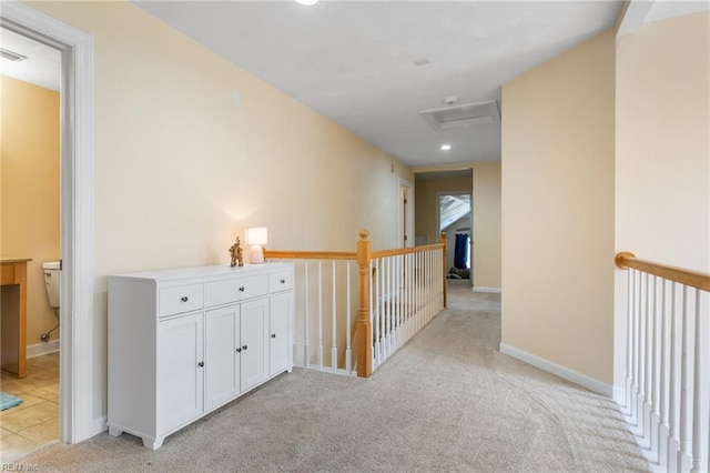 corridor with light colored carpet, visible vents, attic access, an upstairs landing, and baseboards