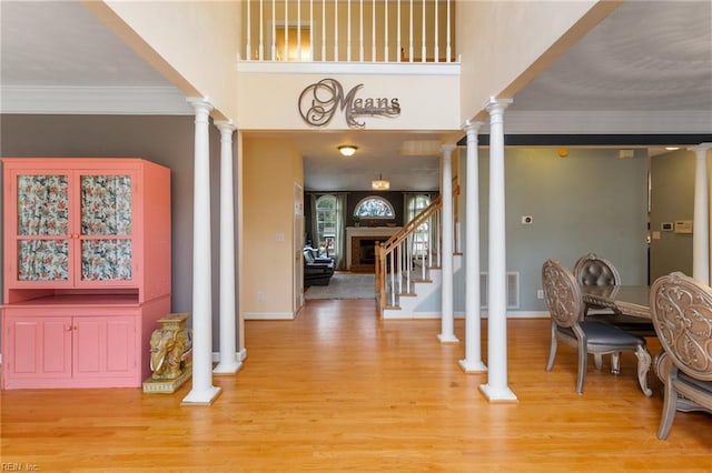 entrance foyer featuring decorative columns, stairway, light wood-style flooring, and ornamental molding