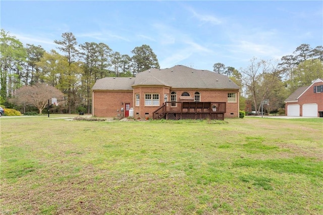 rear view of house with a detached garage, crawl space, brick siding, a deck, and a lawn
