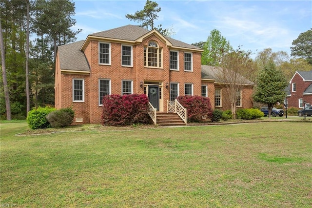 colonial house featuring a front yard and brick siding