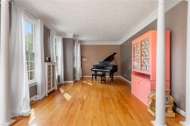 sitting room featuring baseboards, light wood-style flooring, ornate columns, and ornamental molding
