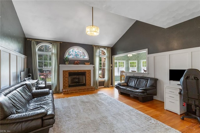 living area featuring a decorative wall, light wood finished floors, a wainscoted wall, and a healthy amount of sunlight