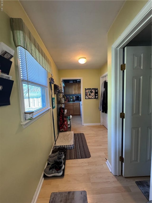 hallway featuring light wood finished floors and baseboards