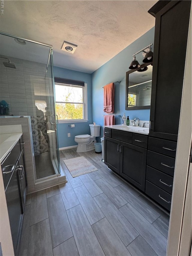 full bathroom with toilet, vanity, a shower stall, and wood tiled floor