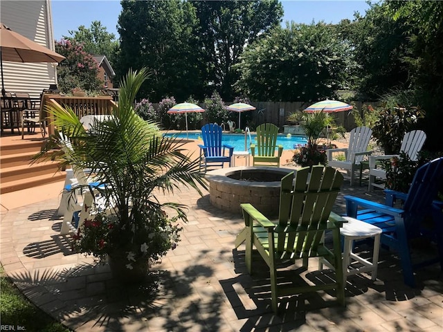 view of patio featuring a community pool, fence, and an outdoor fire pit