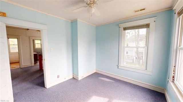 carpeted empty room with crown molding, a ceiling fan, baseboards, and a wealth of natural light