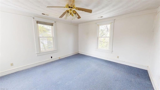carpeted spare room with a ceiling fan, baseboards, and a wealth of natural light