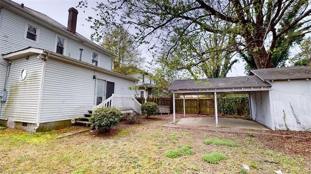 rear view of property featuring fence, a chimney, a patio area, a carport, and a yard