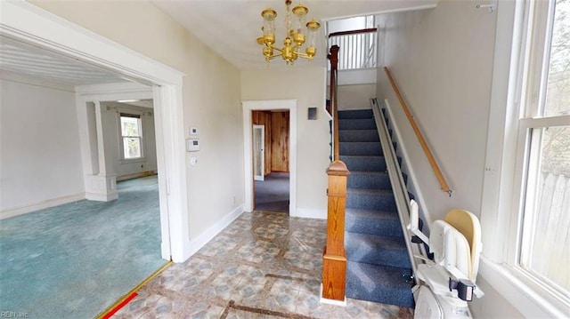stairs featuring an inviting chandelier and baseboards