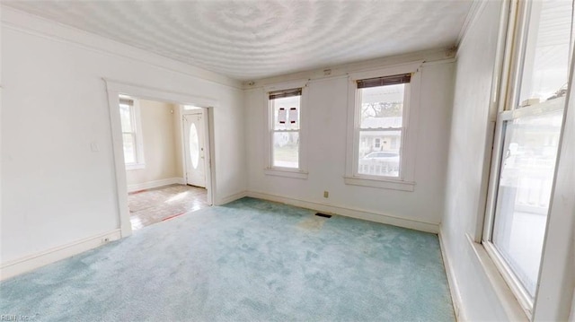 spare room featuring baseboards, light colored carpet, and visible vents