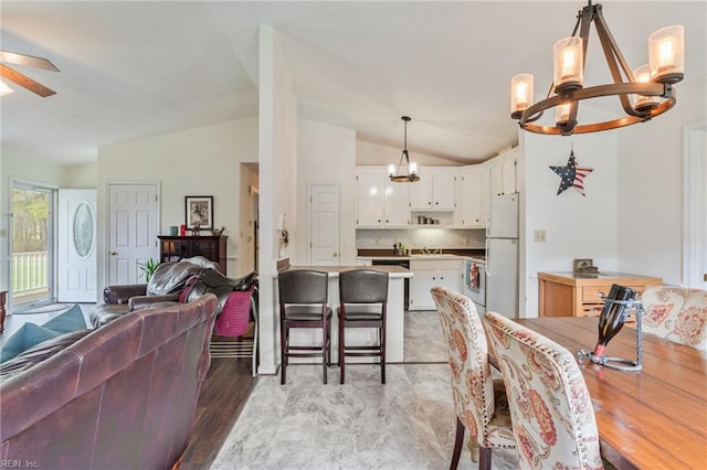 dining area with vaulted ceiling and ceiling fan with notable chandelier