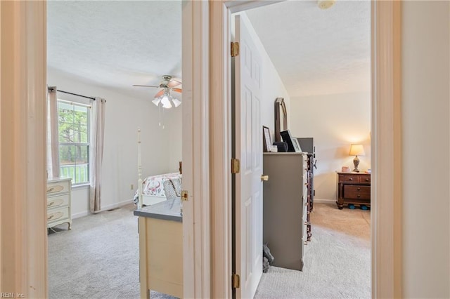 hallway with carpet, a textured ceiling, and baseboards