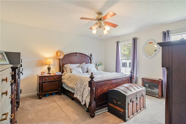 bedroom featuring light carpet, baseboards, and ceiling fan