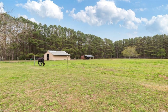 view of yard featuring an outbuilding, a wooded view, and an outdoor structure