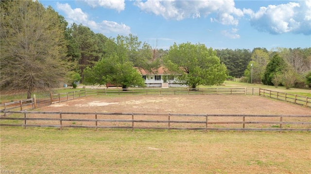 view of property's community with a rural view, an enclosed area, and a lawn