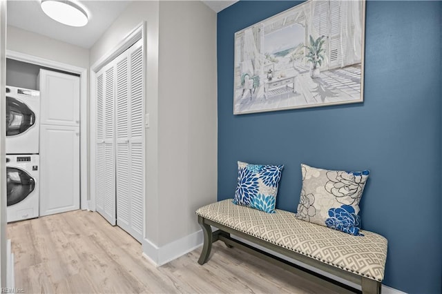 sitting room with stacked washer / dryer, wood finished floors, and baseboards