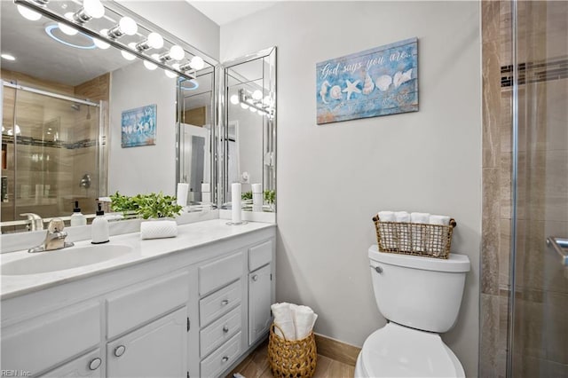 bathroom with a shower stall, vanity, baseboards, and toilet