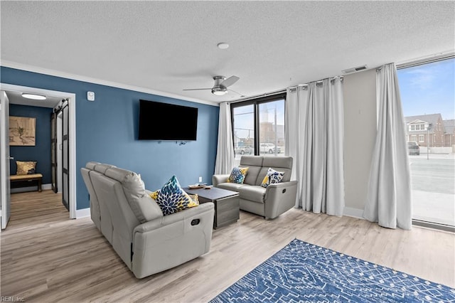 living room with visible vents, light wood-type flooring, a ceiling fan, and a textured ceiling