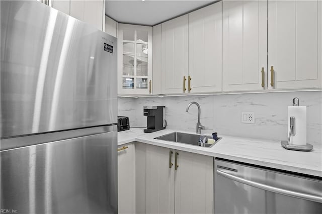 kitchen featuring tasteful backsplash, glass insert cabinets, white cabinetry, appliances with stainless steel finishes, and a sink