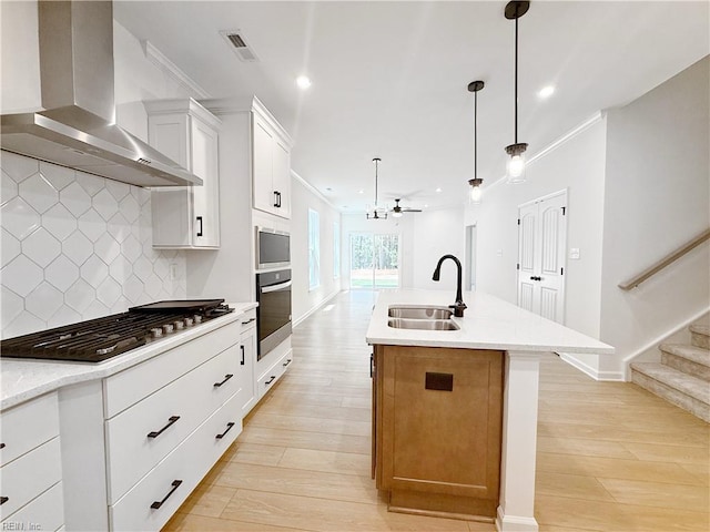 1541 Waltham Ln, Newport News, VA 23608 - kitchen featuring wall chimney range hood, appliances with stainless steel finishes, a center island with sink, tasteful backsplash, and light wood finished floors