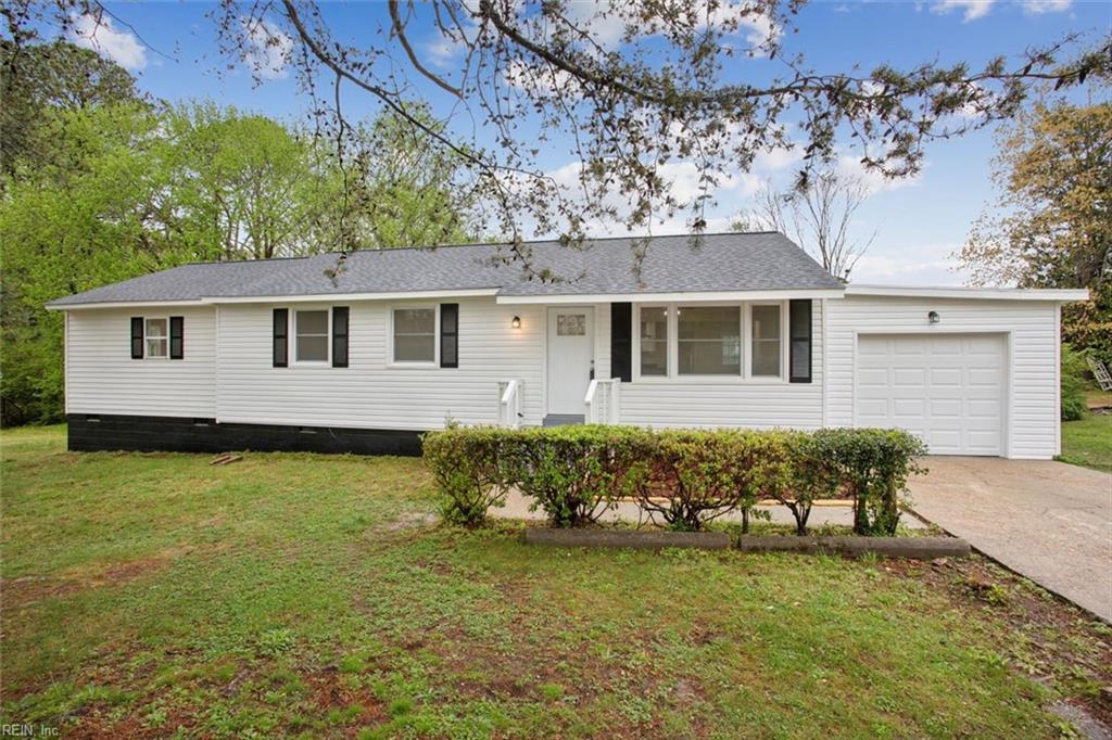 ranch-style home featuring a garage, a shingled roof, a front lawn, and concrete driveway